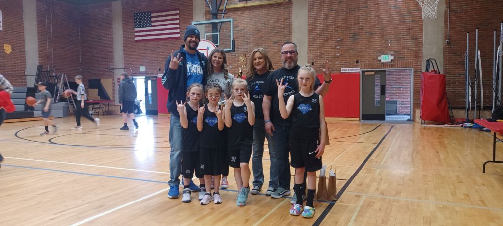 group of grade school basketball players in Tenino standing on the basketball court with their coach