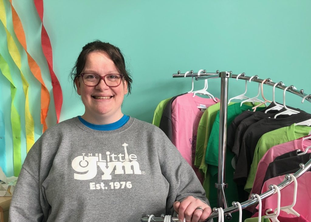 The Little Gym owner Melissa Lilley smiling by a clothing rack