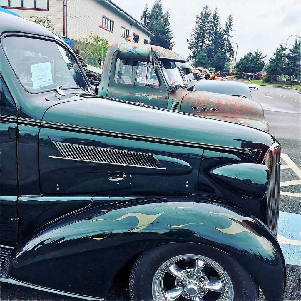 a line of vintage cars with a green one with flames close up