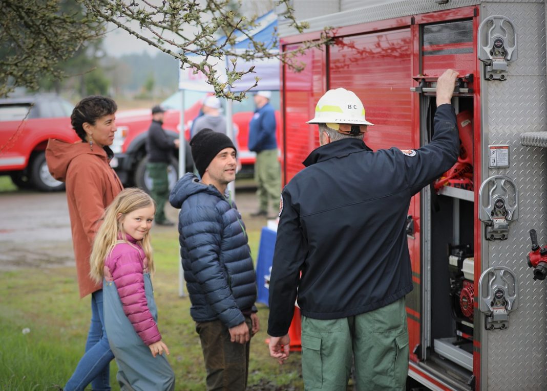 firemen showing a group of people something on a fire truck