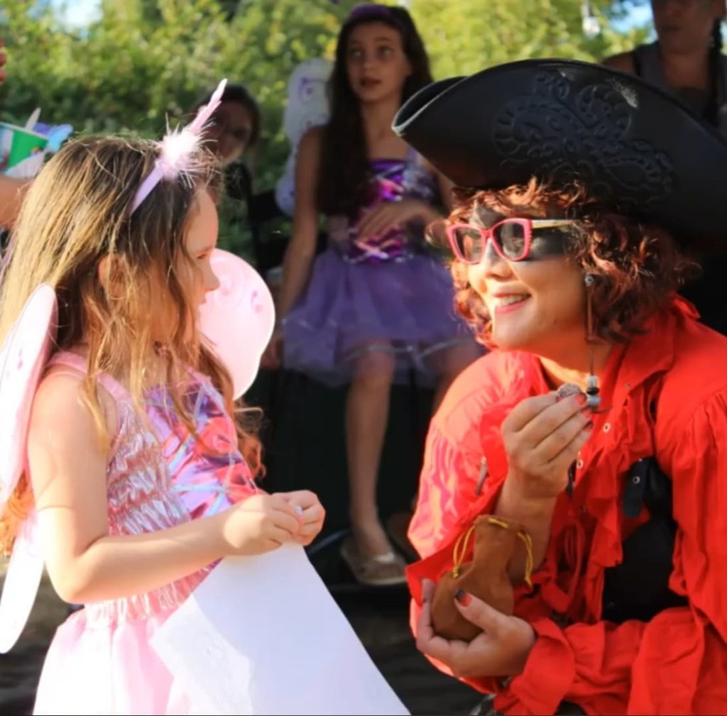 little girl dressed as a fairy with a woman dressed a pirate crouched in front of her.