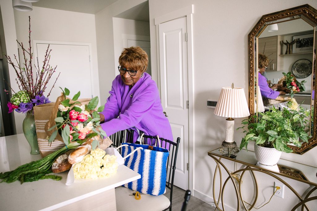 Adlene unpacking a bunch of fresh cut flowers on her kitchen island at Harbor Heights 55+ Community.