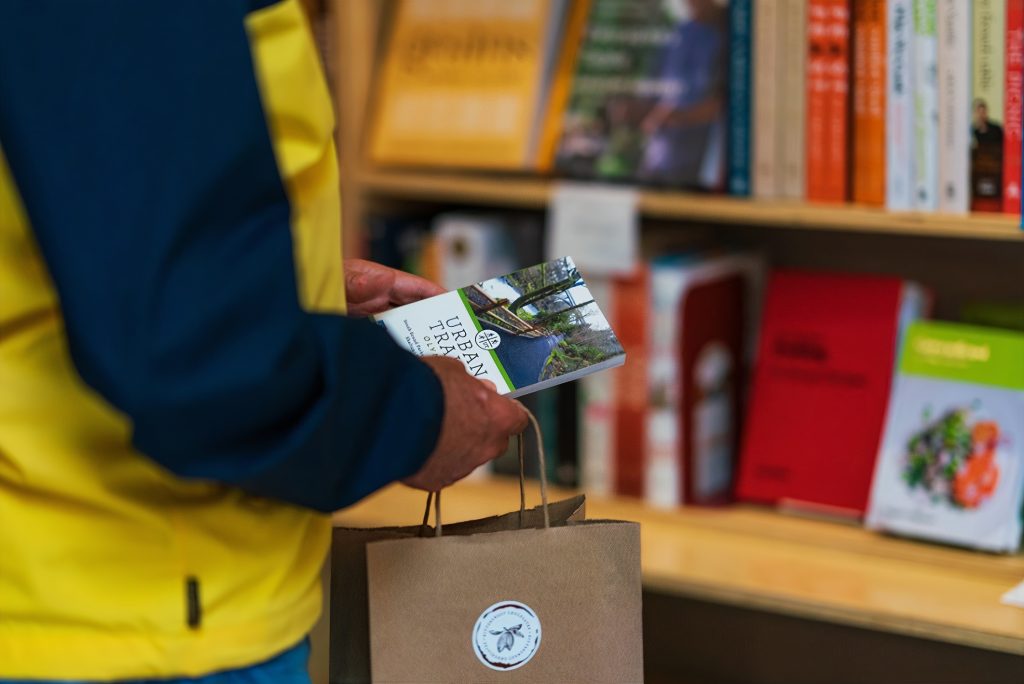 a close of up someone's right hand with a paper handled bag and holding a book