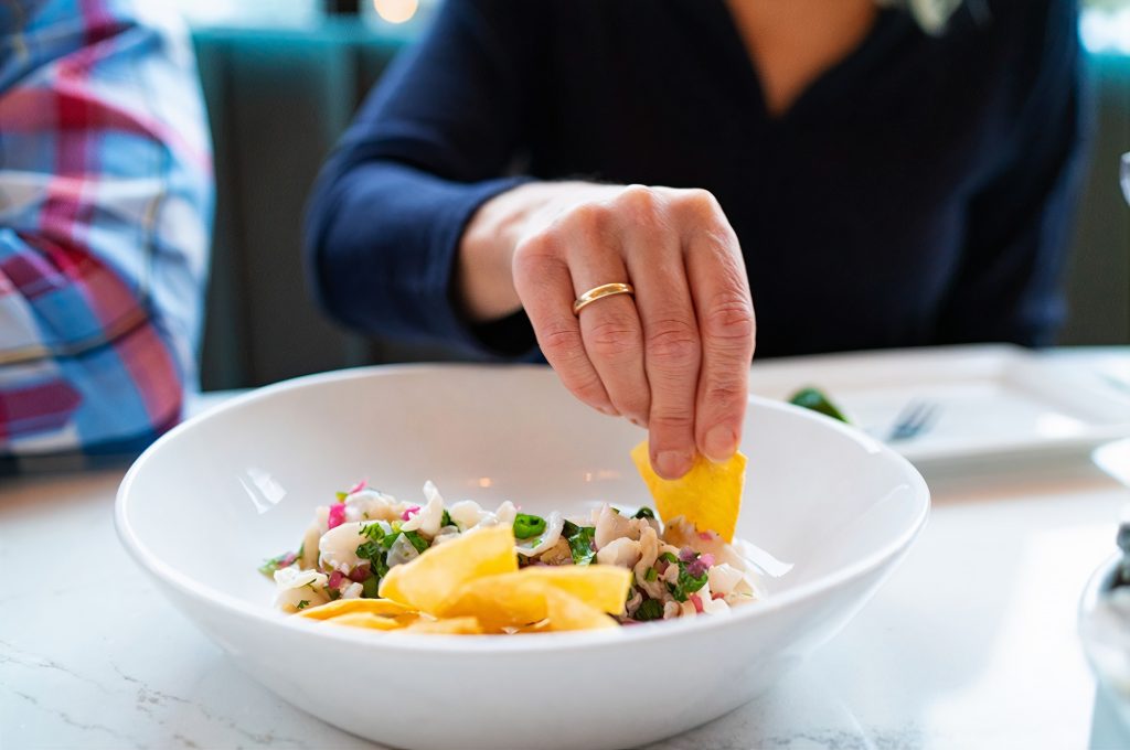 Chelsea Farms seafood bowl with someone dipping a chip into it