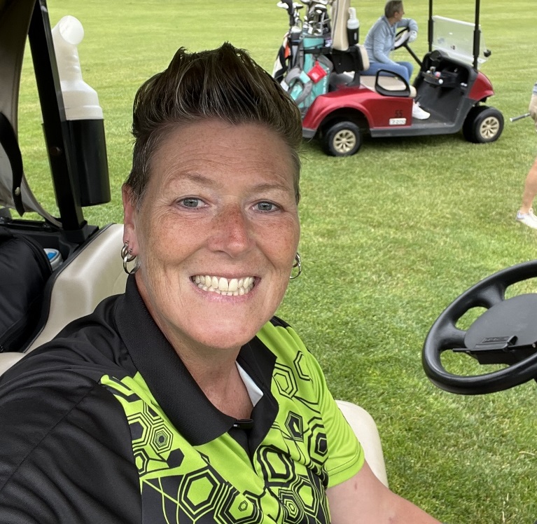 Kat Scheibner taking a selfie in a golf cart on a course