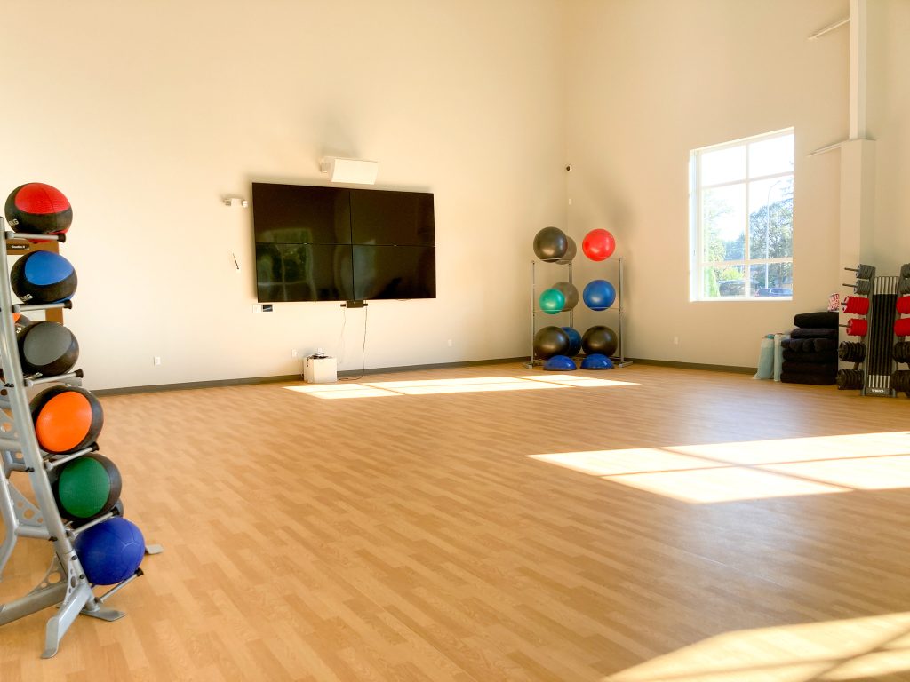 empty fitness studio at Steamboat Tennis and Athletic Club with yoga balls, and mats in carts along the wall and a flat screen TV.