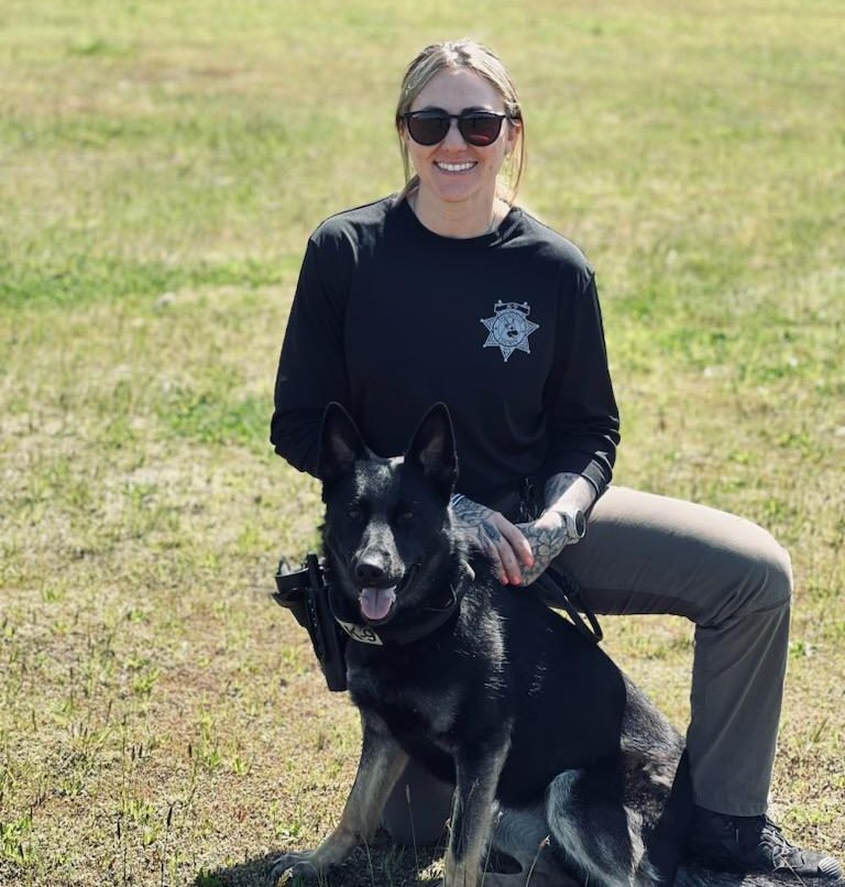 Madison Dillion kneeling on grass with her K9 Partner