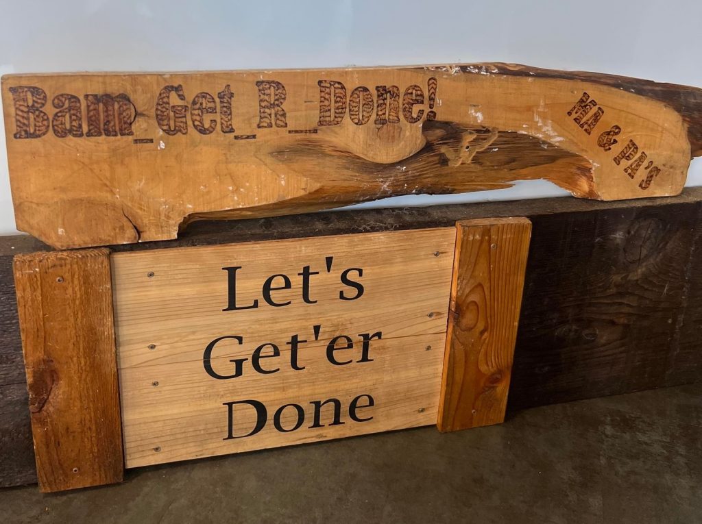 wooden plaque with the words 'Let's Get'er Done' burned onto it.
