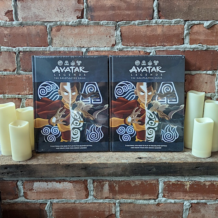 Two 'Avatar Legends' game boxes on a brick ledge with three pillar candles on either side