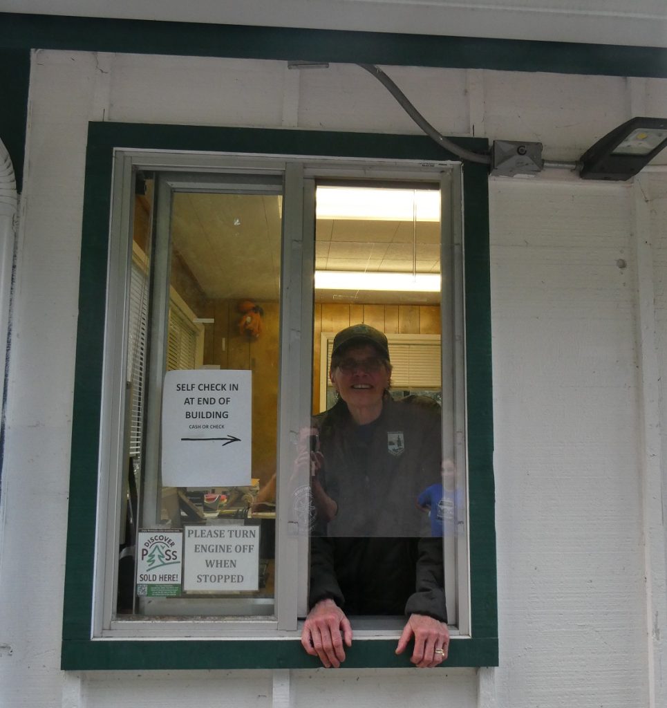 Park Aid Anne Fruechte inside her park hut with the window upen and her hands on the sill