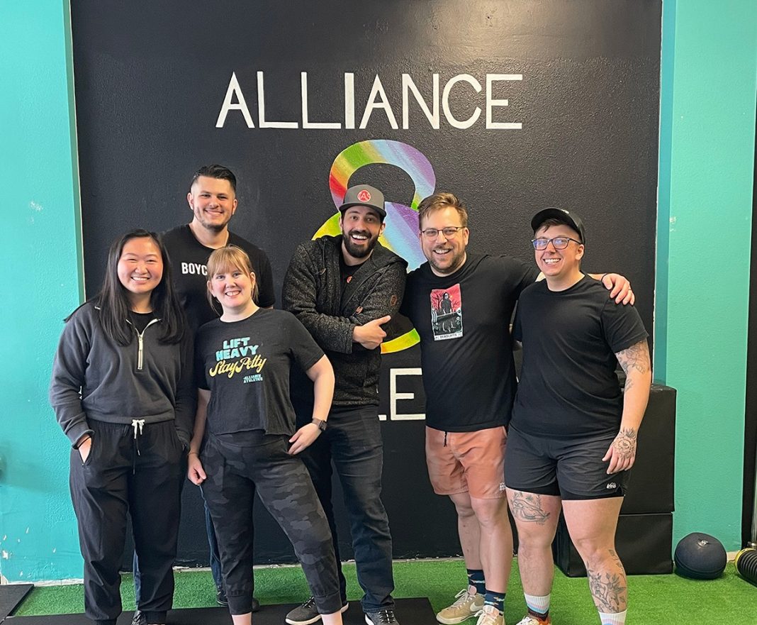 group of six people standing in front of the 'Alliance Athletics