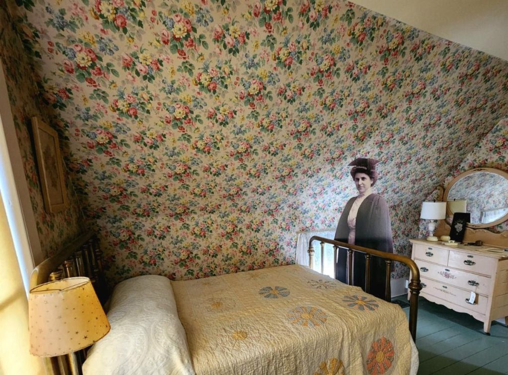 Bigelow House bedroom with floral wallpaper and a small bed and vanity