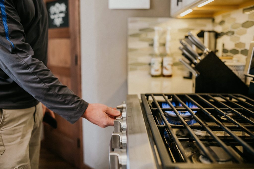 person turning on a gas range in a kitchen