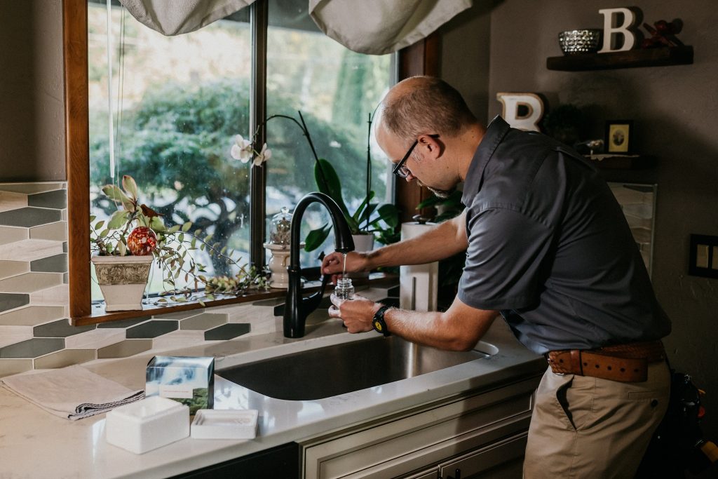 Boggs Inspection technician filling a small jar with water from a kitchen sink