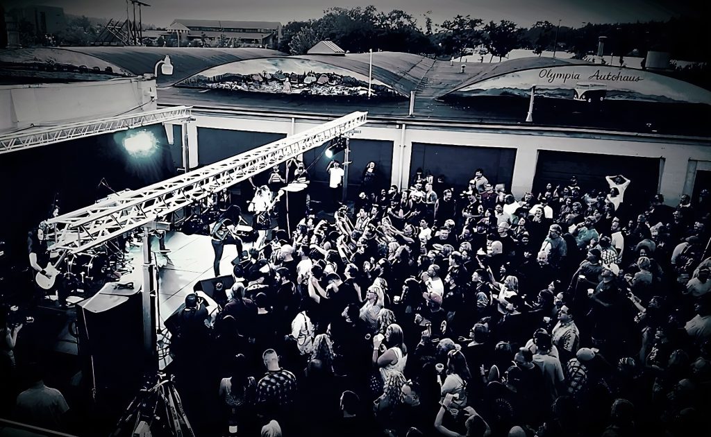 black and white aerial shot of a concert with a rock band and a large crowd below