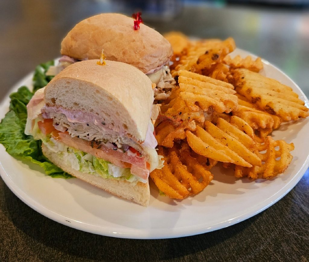 turkey sandwich with criss-cross fries on a white plate