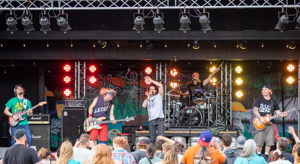 Band performing on an outdoor stage to a large crowd