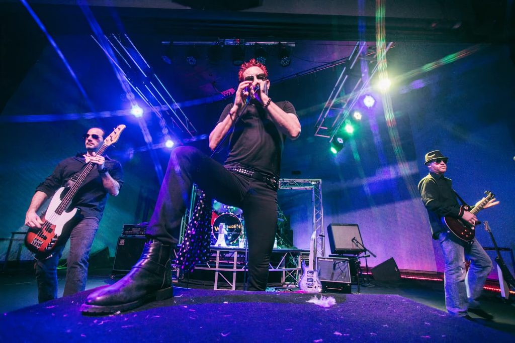 Rock band performing on a stage in green and purple lighting