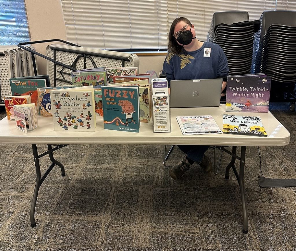 person sitting at a folding table with lots of boxes on it