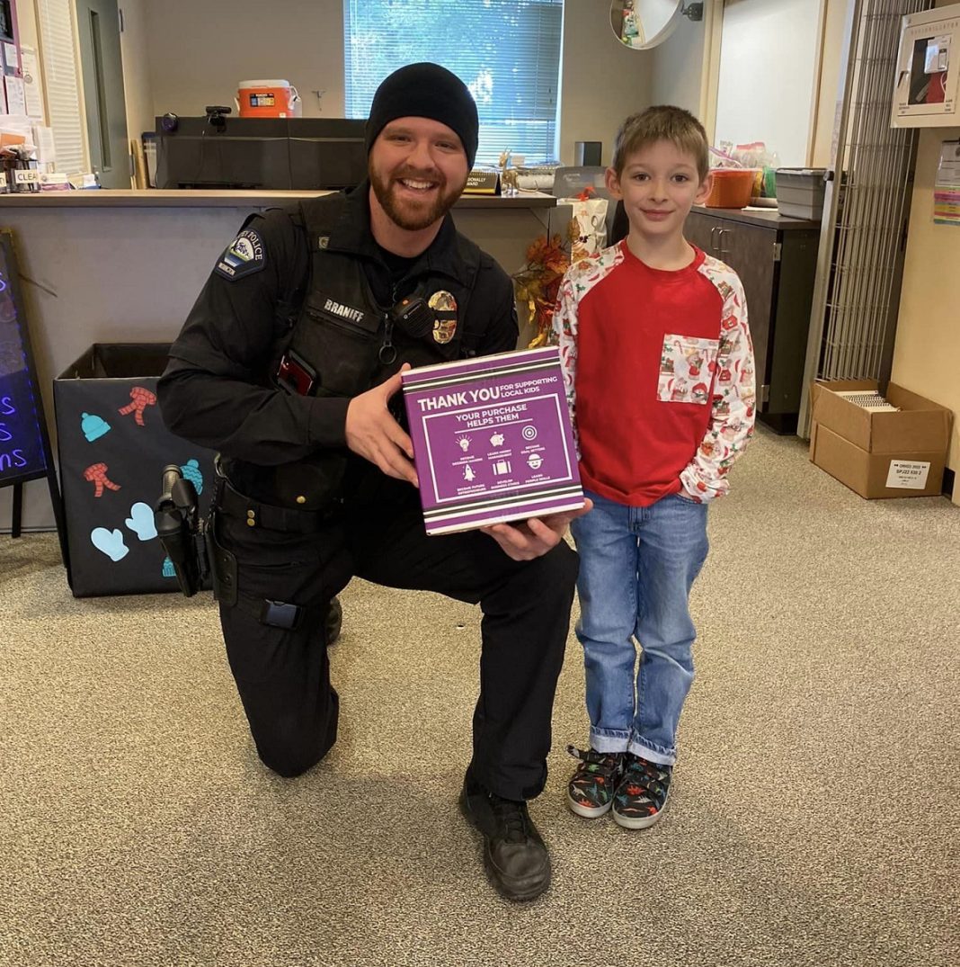 a little boy poses with a security officer who is kneeling next to him holding a plaque that says 'Thank you'