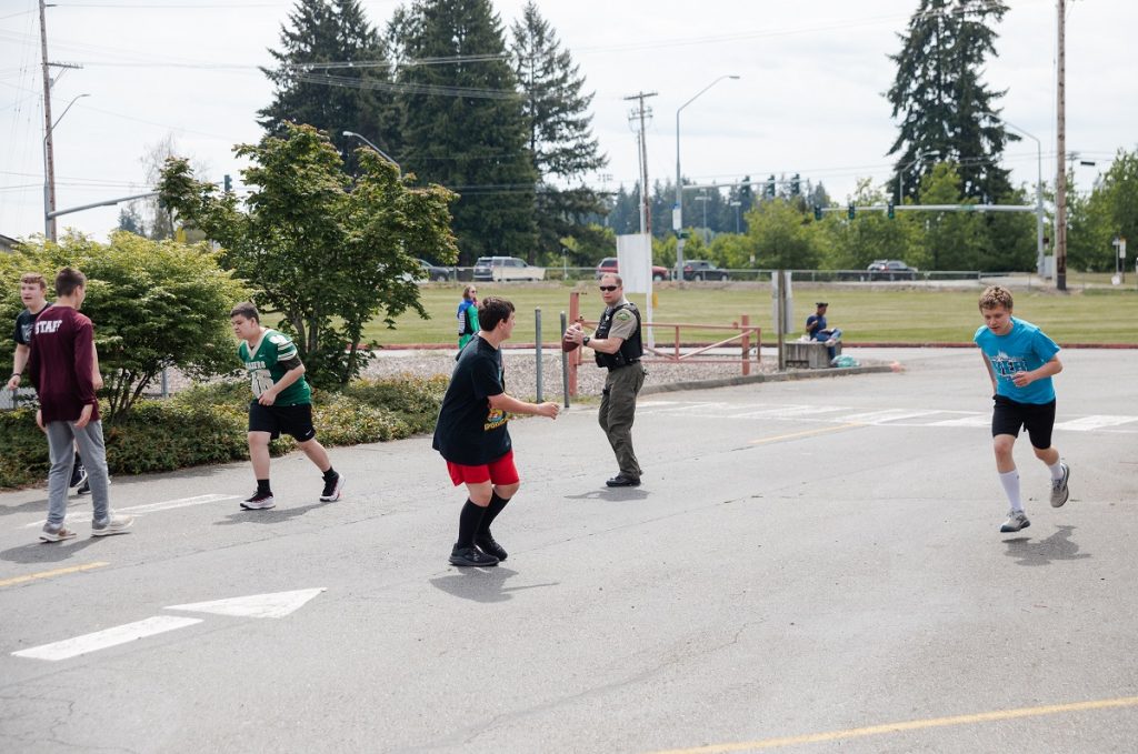 kids play football on pavement with a security guard