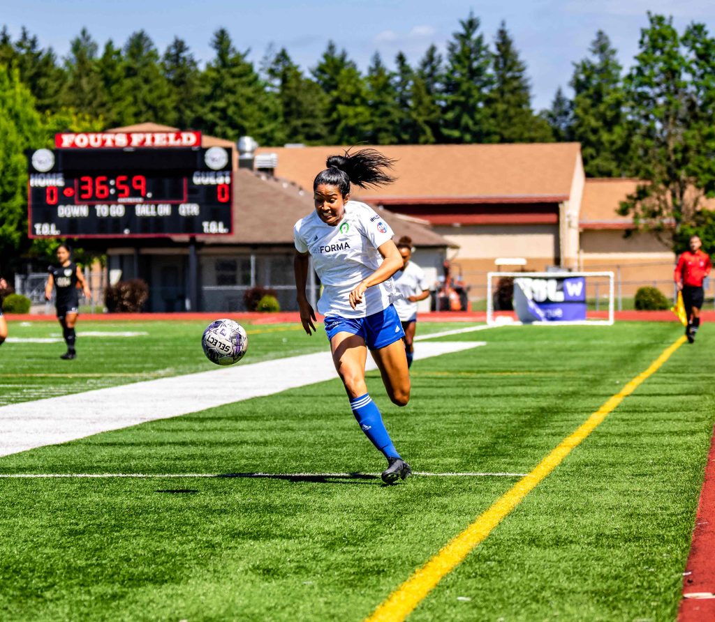 woman soccer player running down the field with the ball