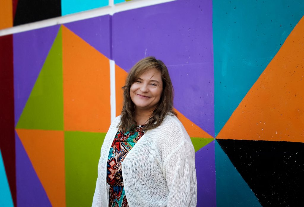 Nicole (Nikki) Francis standing by a geometric background in lots of colors