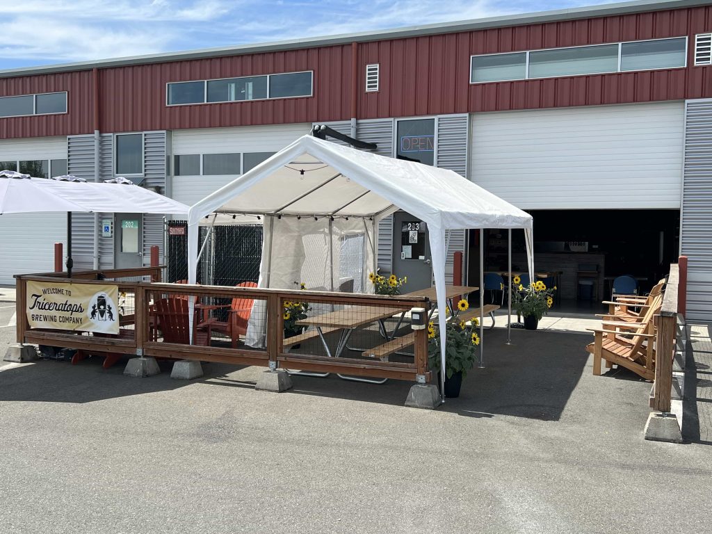 white tents outside an industrial building with picnic tables underneath it