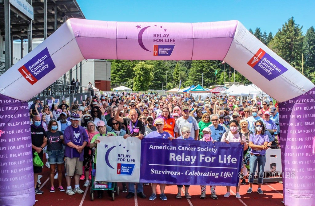 huge group of people under the blow-up Relay for Life archway holding a Relay for Life banner