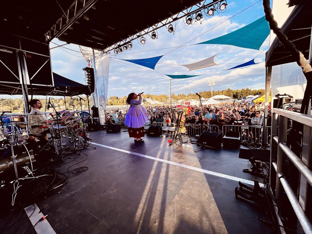 Person in a purple dress singing on an outdoor stage