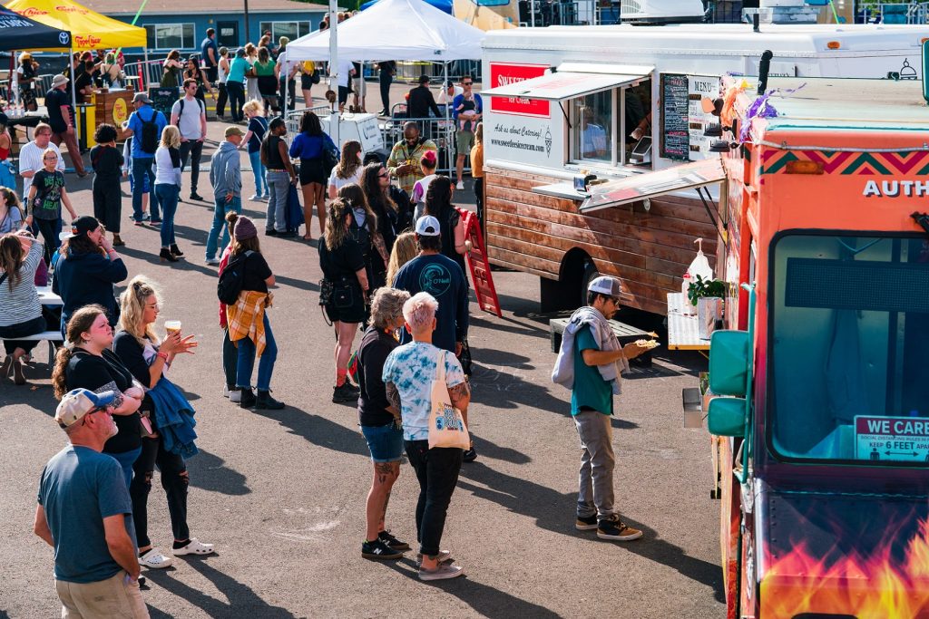 people milling around a line of food trucks outside