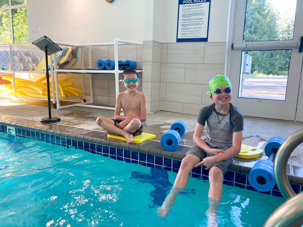 a couple kids sitting poolside at Steamboat Tennis & Athletic Club, one with their legs in the pool