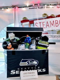 Table with a seahawks cooler full of bottles, snacks and other items