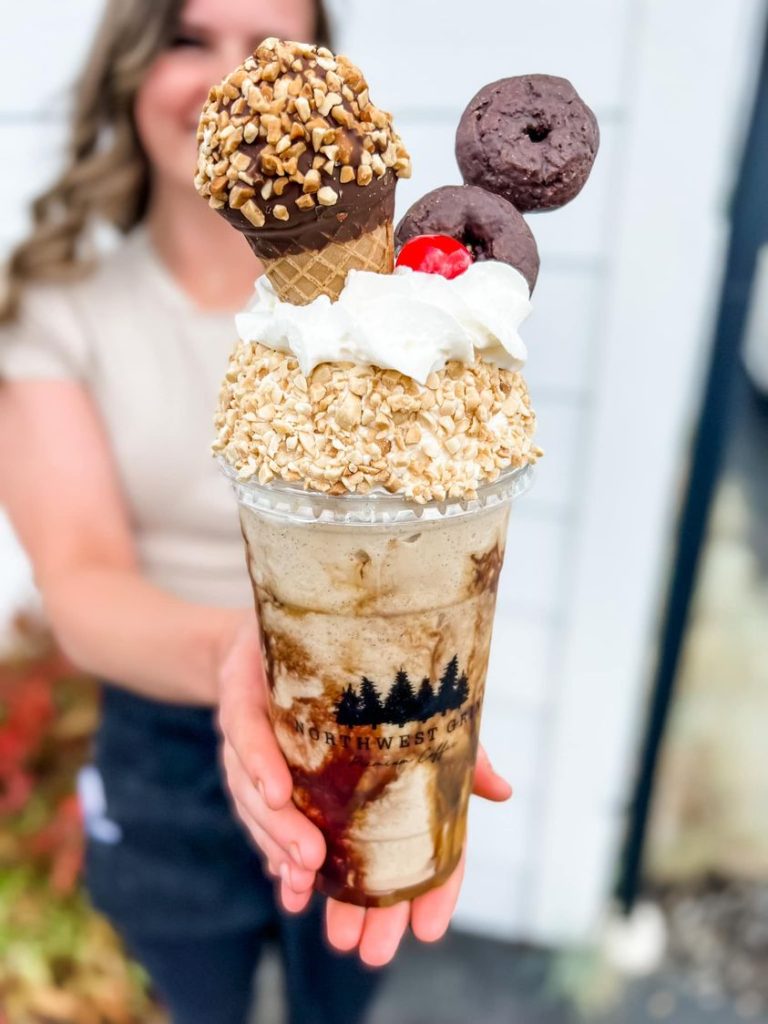 large iced coffee drink with a drumstick ice cream cone and two chocolate mini donuts coming out of the whipped cream