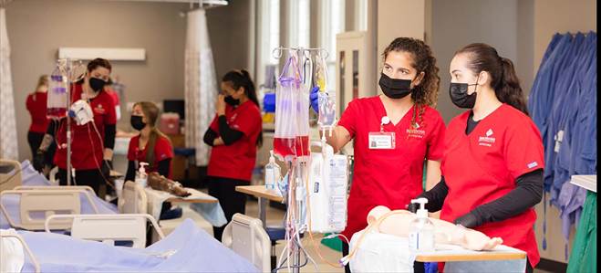 a group of nurses in red scrubs with black masks standing at different beds with IVs