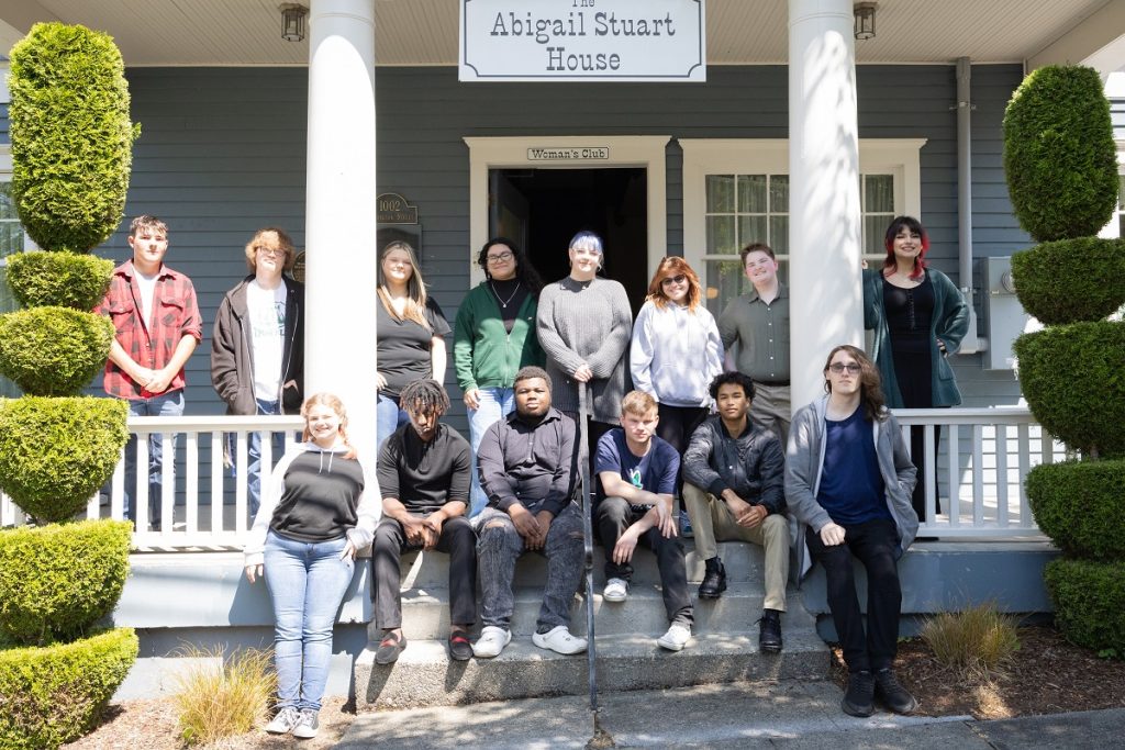 The 2023 All Kids Win Scholarship winners pose on the porch of the Abigail Stuart House, some sitting on the steps.