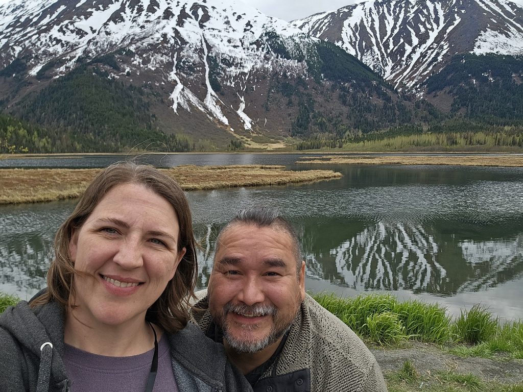 Jessica Kammeyer with a man next to her taking a selfie with a mountain and lake in the background