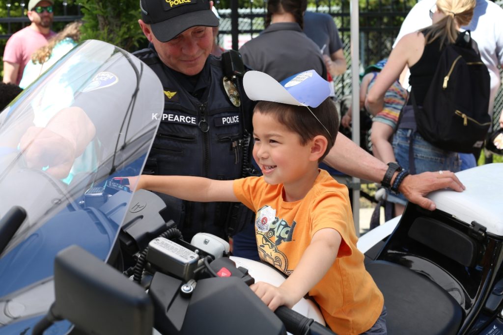 small kid sitting on a motorcycle with a policemen next to him.