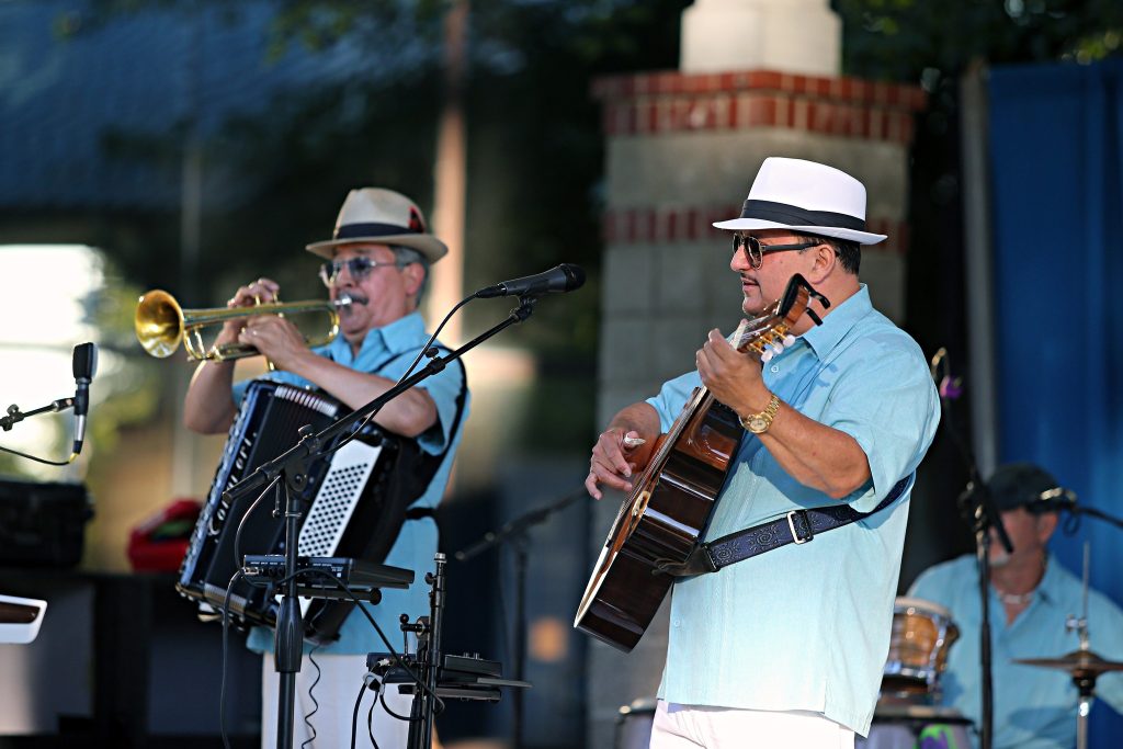 one person playing a guitar and another holding an accordion while playing a trumpet