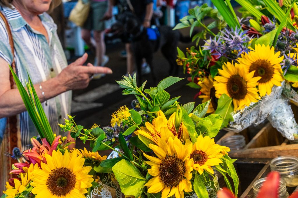 bunches of sunflowers in a wooden cart with a woman pointing at them