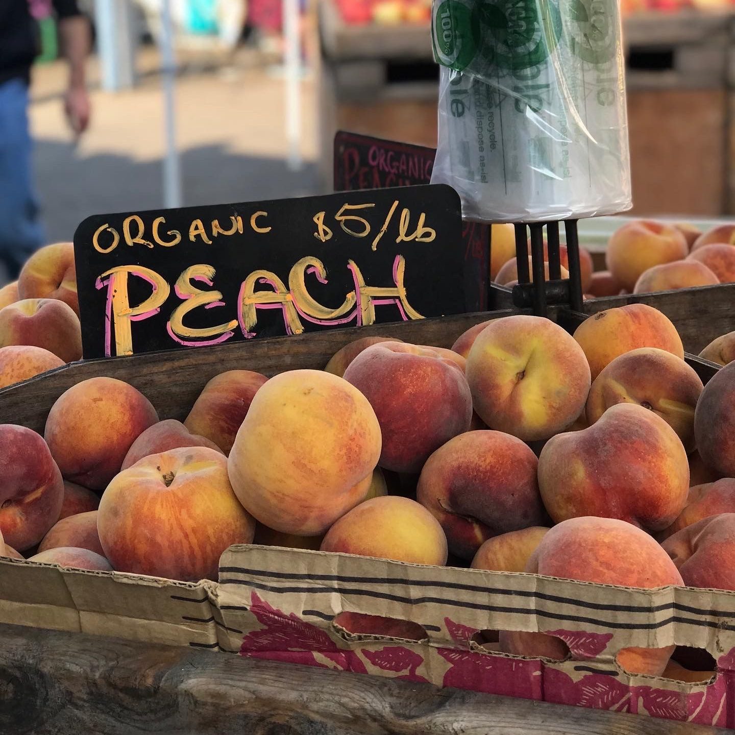 a large crate of peaches with a sign on top of them that says, 'organic $5/pound Peach'