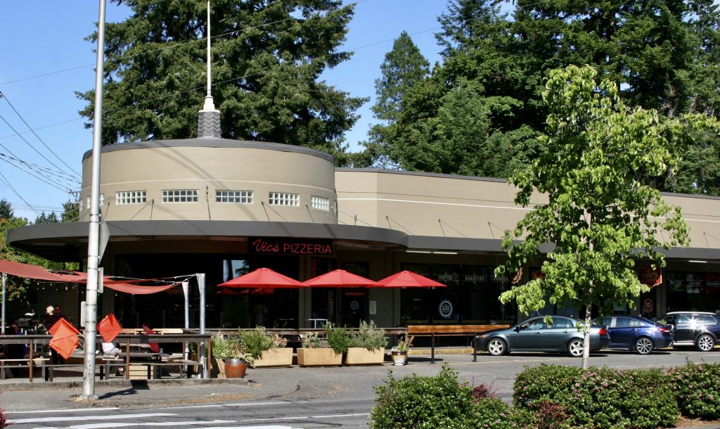 Olympia Coffee Roasters building from across the parking lot, three red umbrellas out front with tables