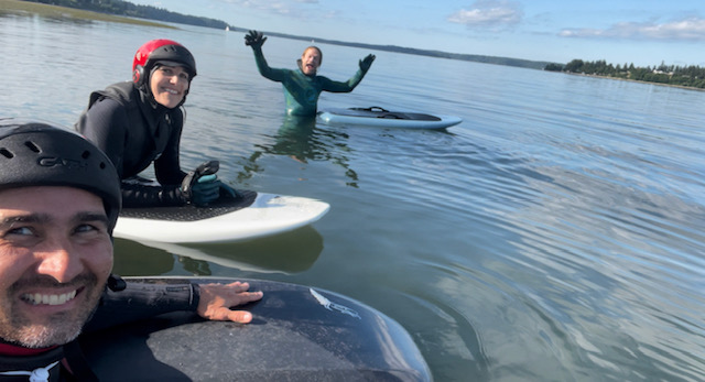 three people, two on boards, one in the water next to a board