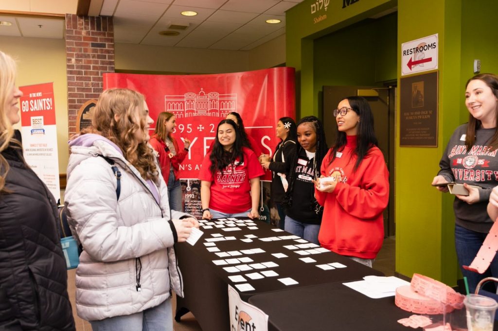 young women standing and smiling and each other on both sides of a long table with a black tablecloth with name tags on it