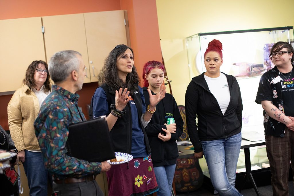 a group of college students listen to a man and women speak as they stand in a circle around them
