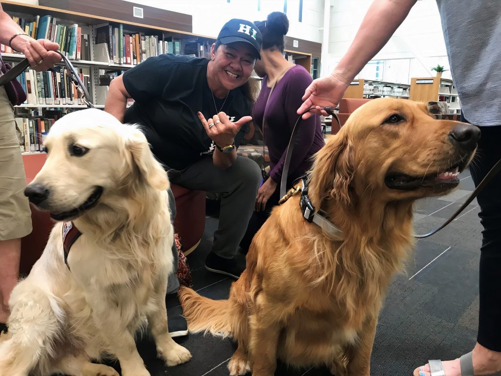 a woman poses with two golden retrievers in the SPSCC library