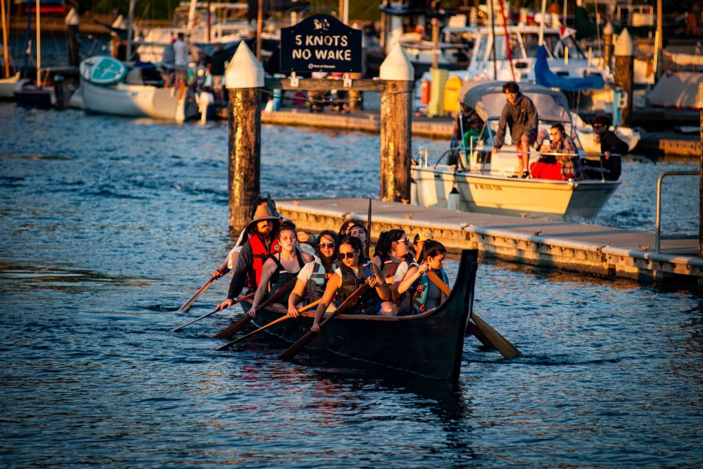 Squaxin Island Tribal members in a canoe by a dock in Puget Sound