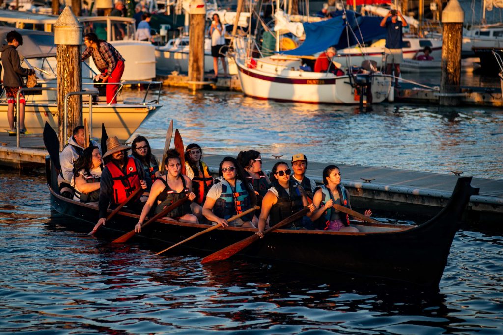 Squaxin Island Tribal members in a canoe by a dock in Puget Sound