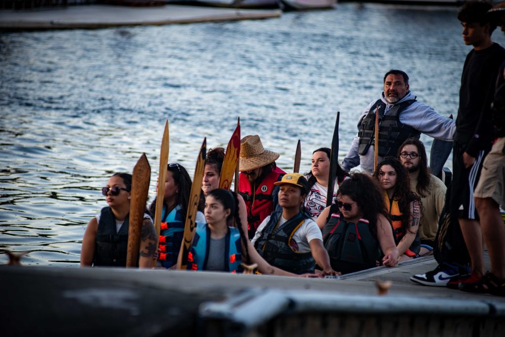Squaxin Island Tribal members in a canoe by a dock in Puget Sound