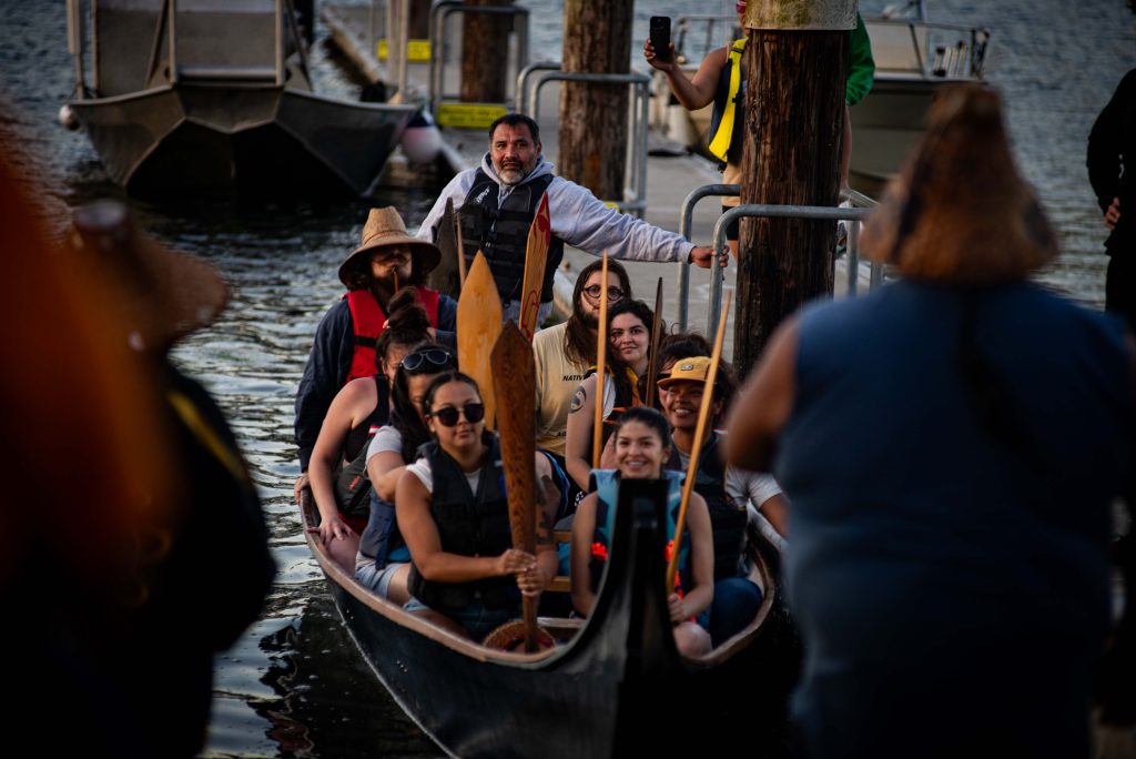 A canoe full of Squaxin Island Tribal members pull up to a dock